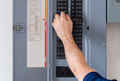 A close-up of a man's arm and hand as he flips a circuit breaker.