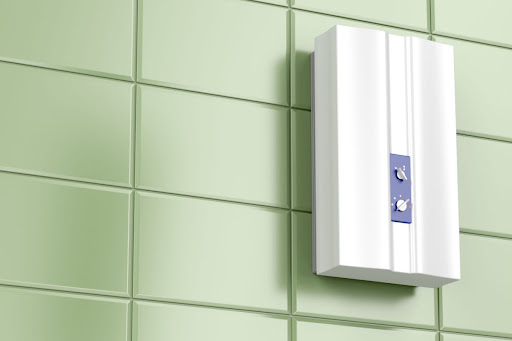White tankless water heater installed in bathroom with green tiles.