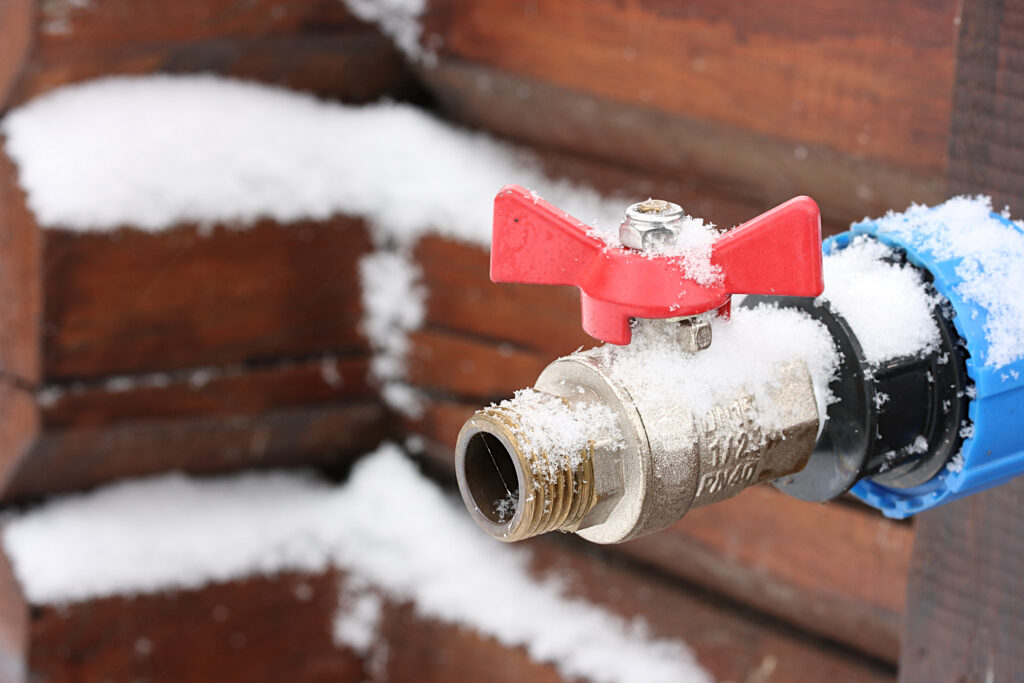 Outdoor spigot covered in frost and snow