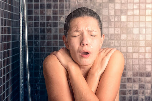 A woman shivering in the shower.