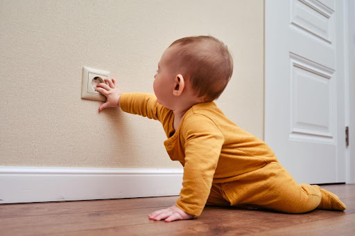 Baby touching electrical outlet