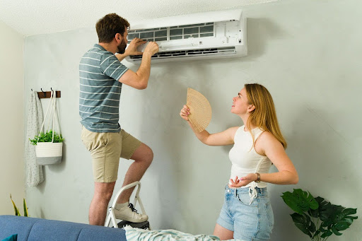 Homeowner looking at short-cycling AC while partner fans herself.