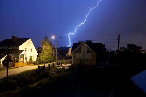 Houses with a lightning strike behind them.